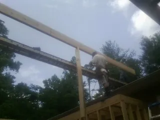 Carpenter setting a ridge beam over a new addition frame in Jamesville